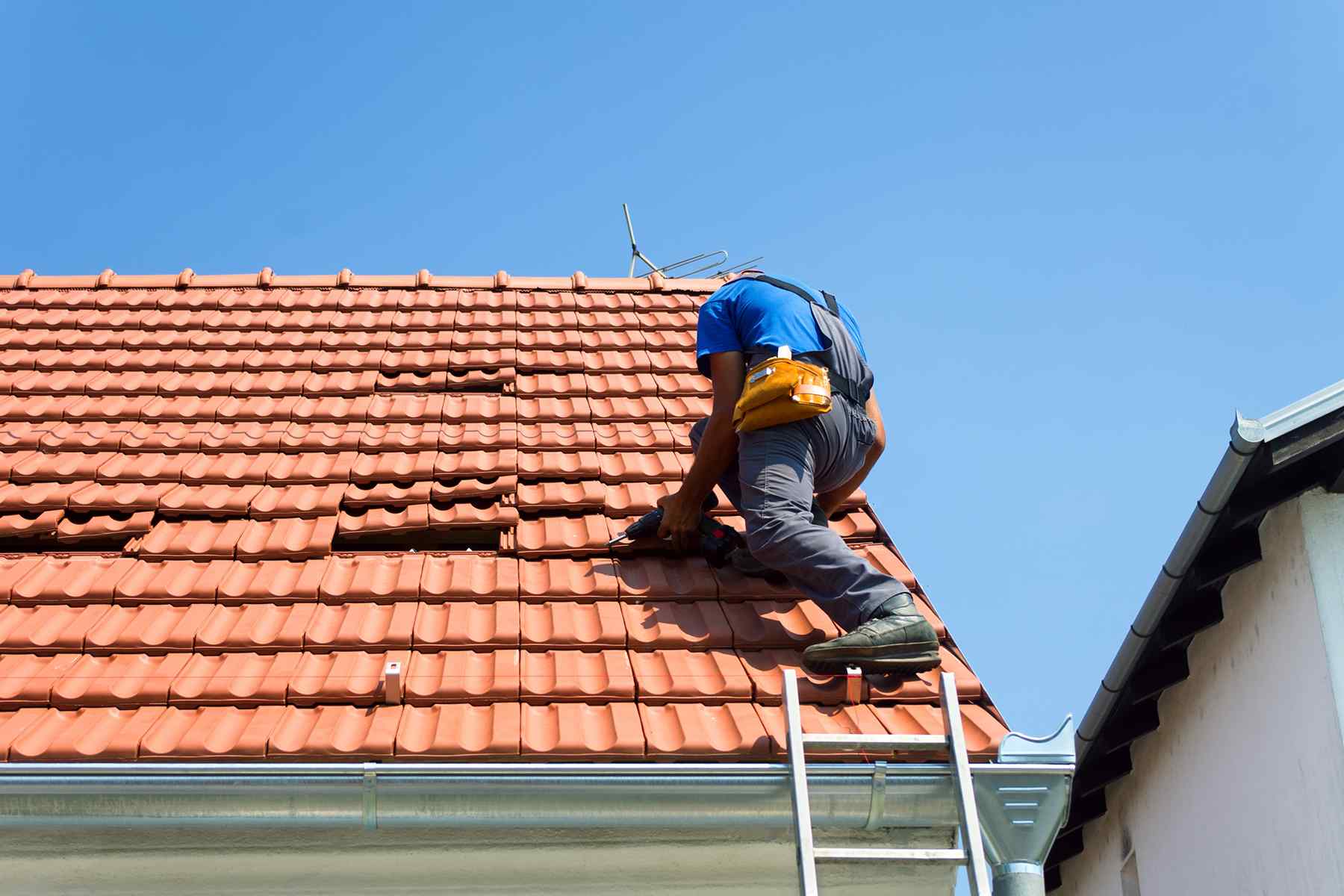 Roofing contractor working on a red tile roof replacement in Costa Mesa, Orange County