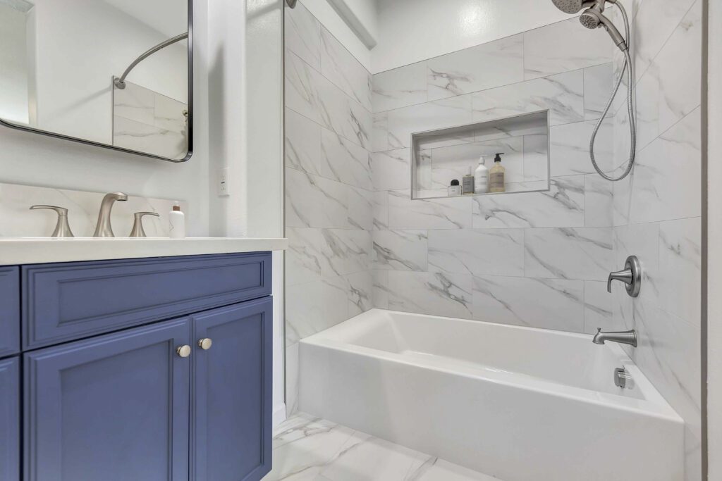 Irvine bathroom remodel with large-format marble-look shower wall tile and recessed niche