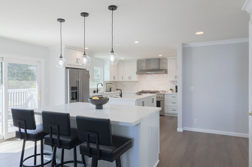 Completed kitchen remodel in Newport Beach featuring white shaker cabinets, quartz countertops, pendant lighting, and stainless appliances.