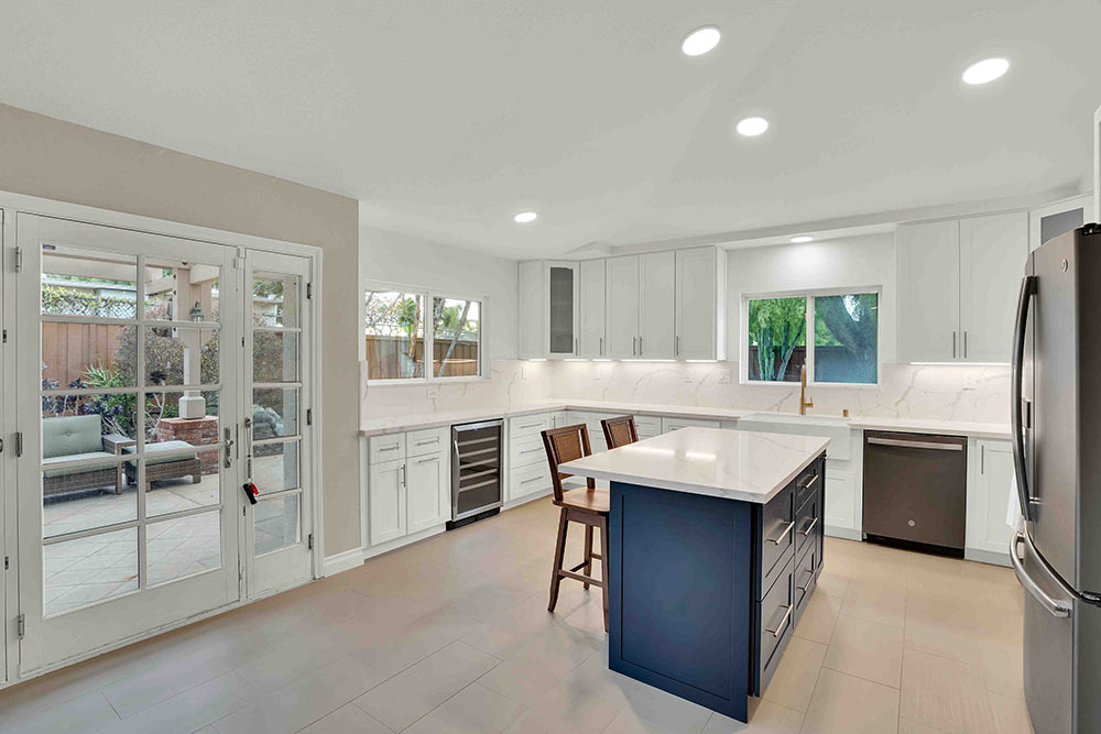 Finished kitchen remodel in Oceanside featuring white shaker cabinets, navy island, quartz countertops, and stainless steel appliances