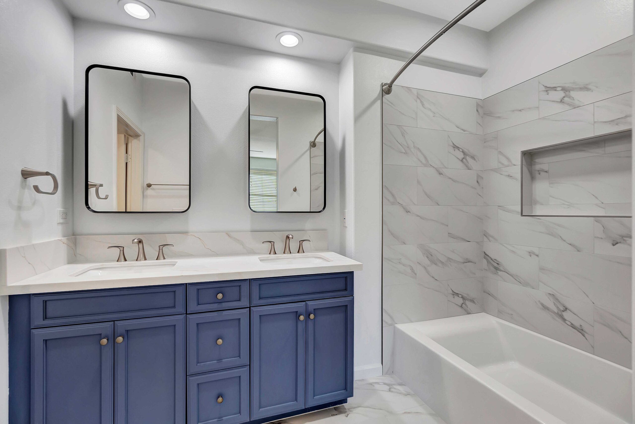 Bathroom remodel with navy vanity cabinets and white marble countertops in Orange County