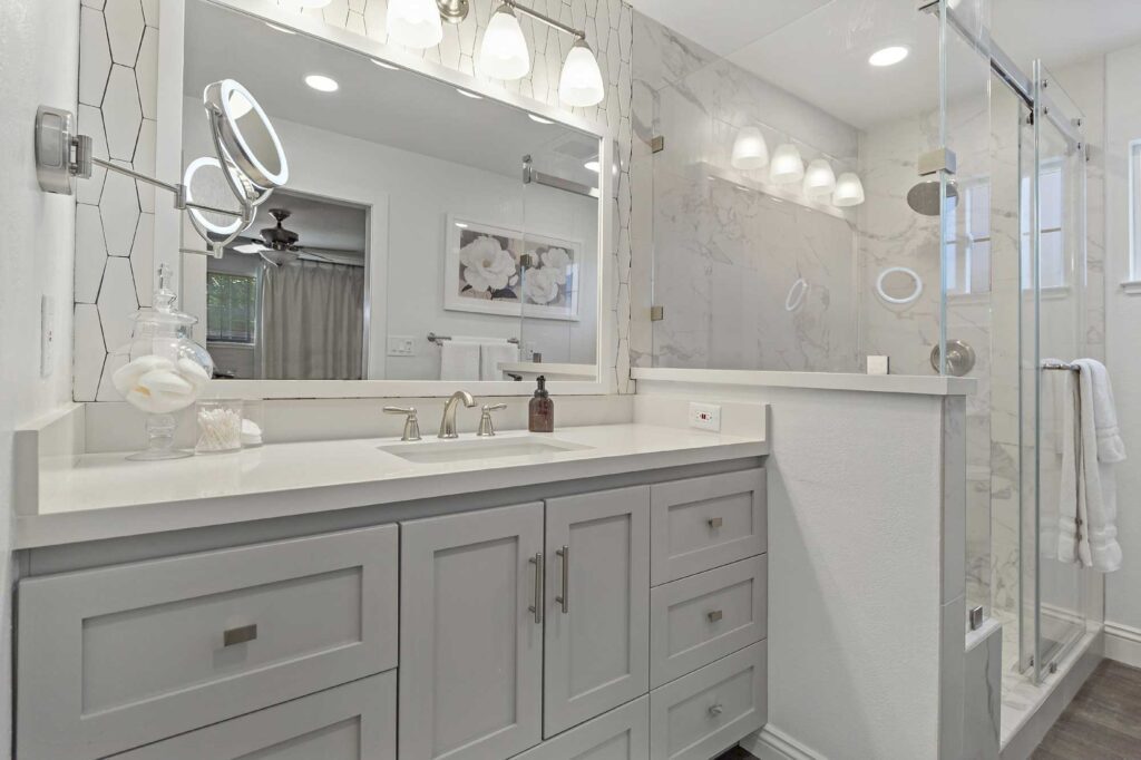 Elegant Mission Viejo bathroom with backlit makeup mirror and modern lighting over double vanity.