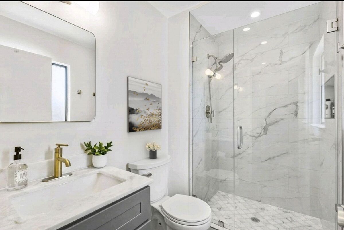 Bathroom remodel in Laguna Niguel featuring gray vanity, marble shower, gold faucet by USA Home Remodeling