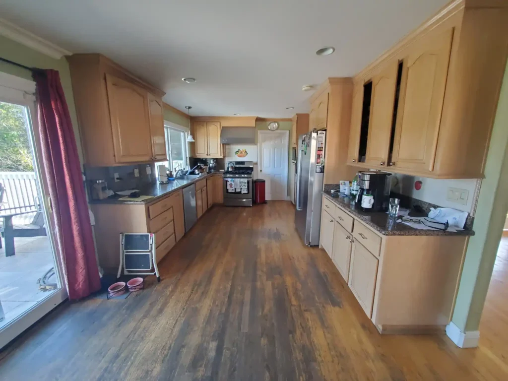 Before kitchen photo with maple cabinets, darker wood floors, and galley layout