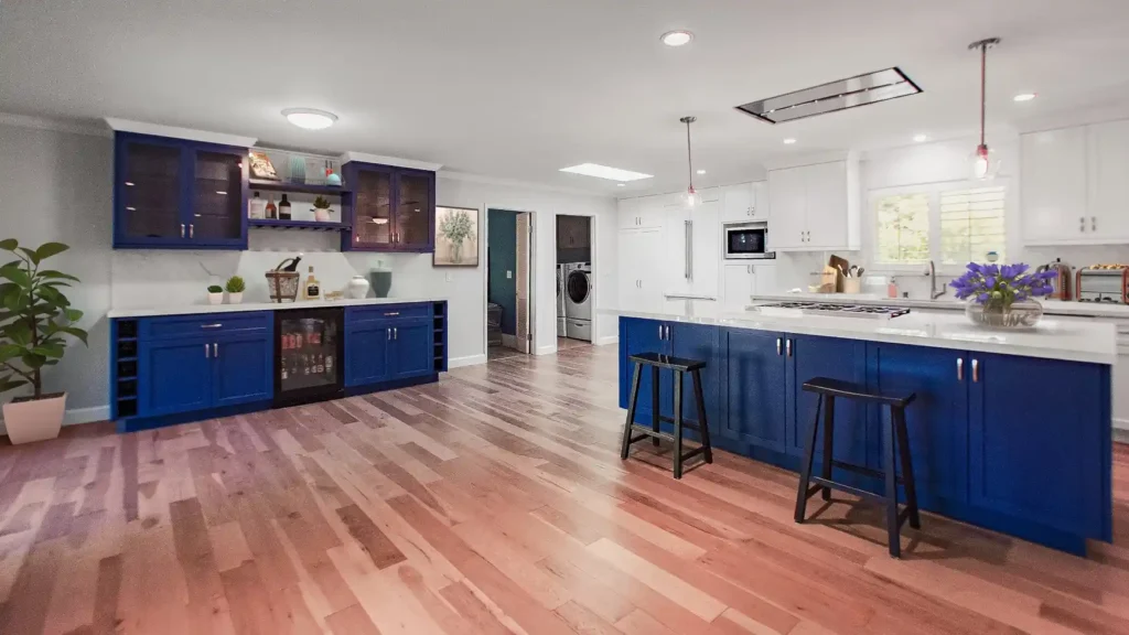 Kitchen remodel with blue island and bar cabinets, white perimeter cabinets, and hardwood floors