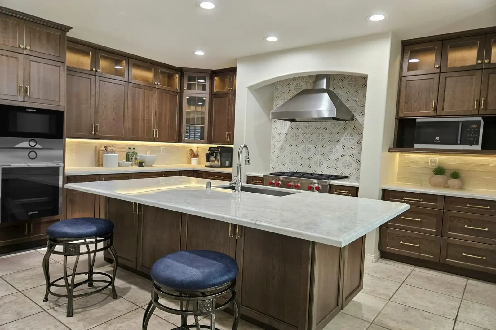 Costa Mesa kitchen remodel - Dark wood cabinets, marble island, decorative tile backsplash, pro-style range