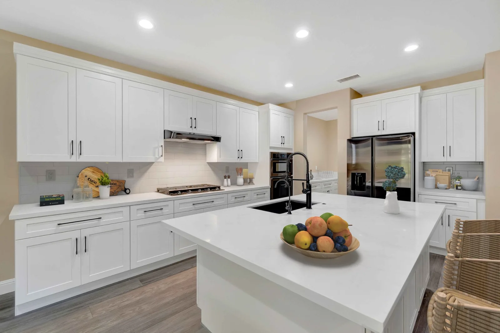 Corona kitchen remodel - White shaker cabinets, quartz island, black fixtures, warm beige walls