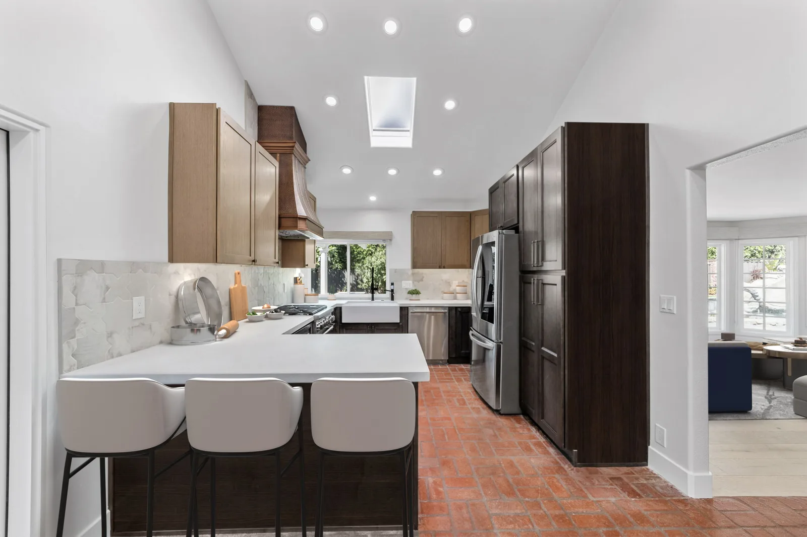 Santa Ana kitchen remodel - Two-tone wood cabinets, copper hood, brick floor, skylight, quartz peninsula