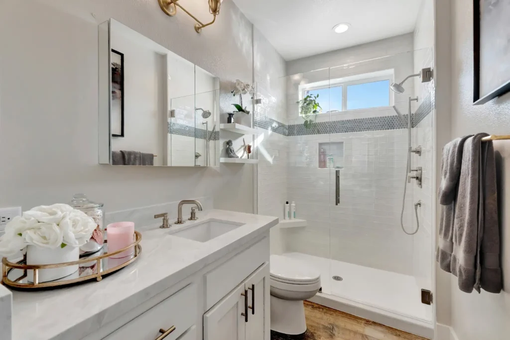 Newport Beach bathroom remodel with quartz vanity, white cabinetry, and frameless glass walk-in shower with subway tile