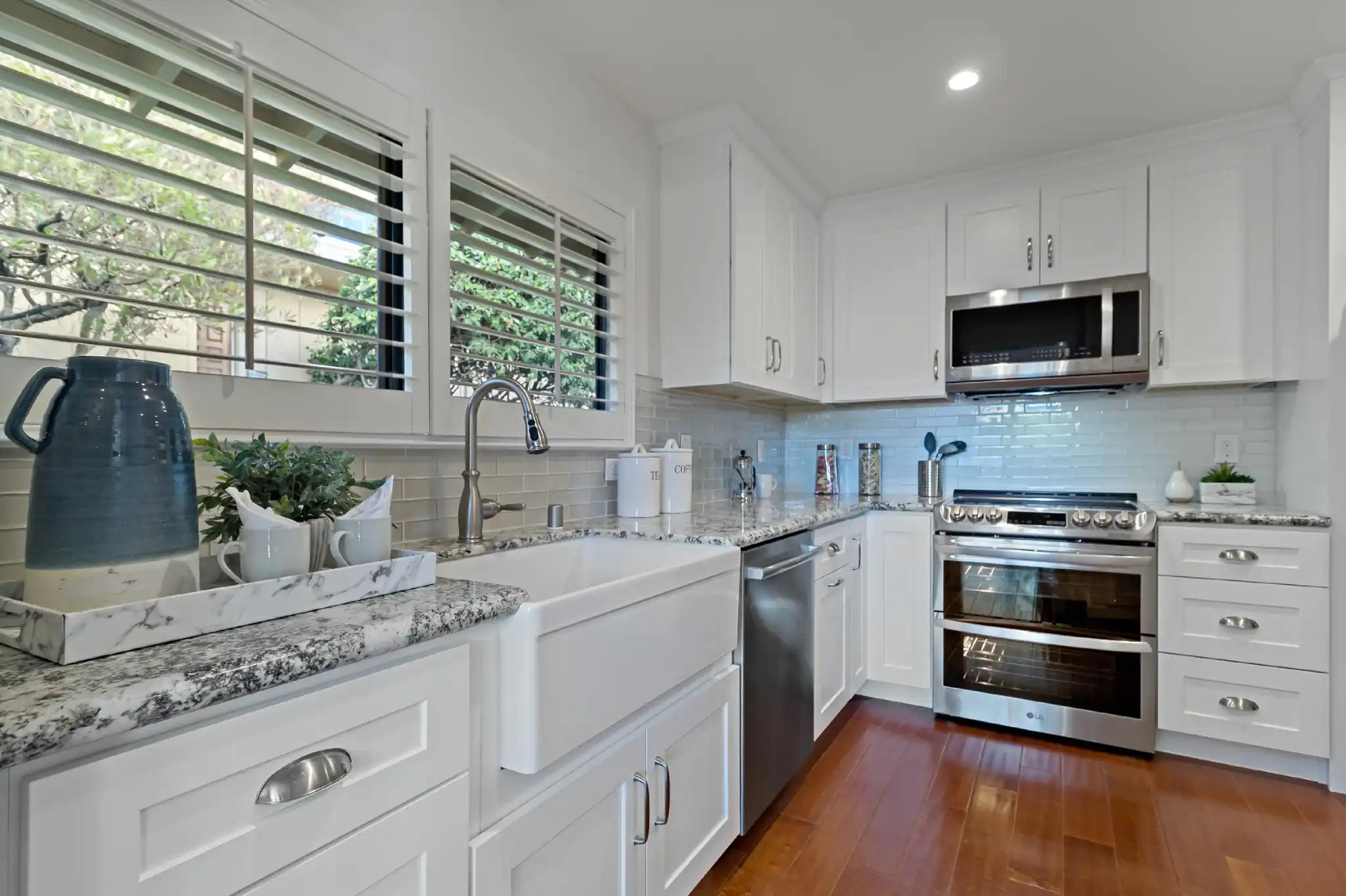 Kitchen remodel in Laguna Hills with white shaker cabinets, farmhouse sink, granite countertops, and subway tile backsplash