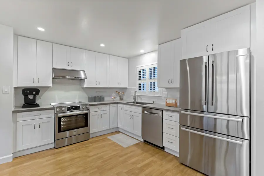 Kitchen remodeling in Laguna Hills — after photo showing white shaker cabinets, quartz countertops, stainless steel appliances, and recessed lighting
