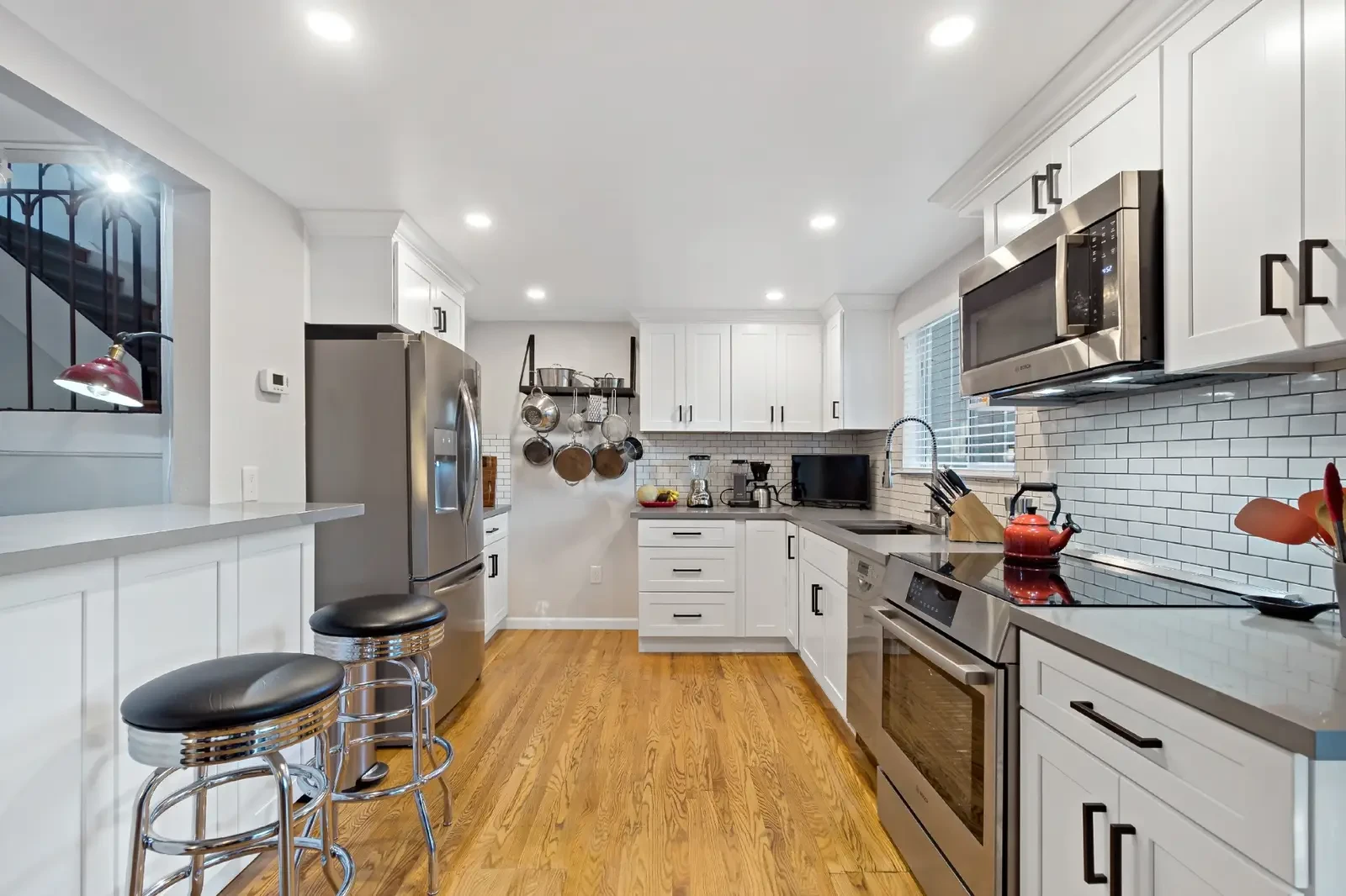 Laguna Niguel kitchen remodel - White cabinets, subway tile backsplash, hardwood floors, bar stools, galley style
