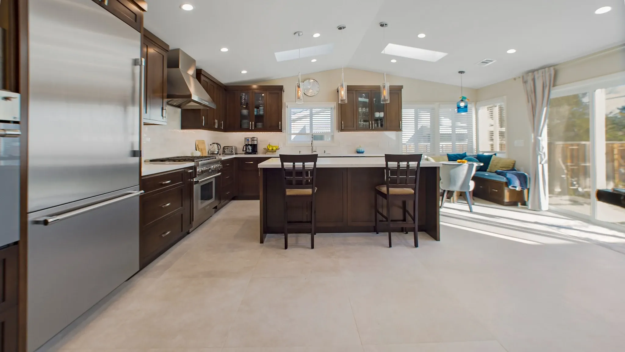 Buena Park remodeling contractor — remodeled kitchen with dark wood cabinets, large island, stainless appliances, and vaulted ceiling with skylights