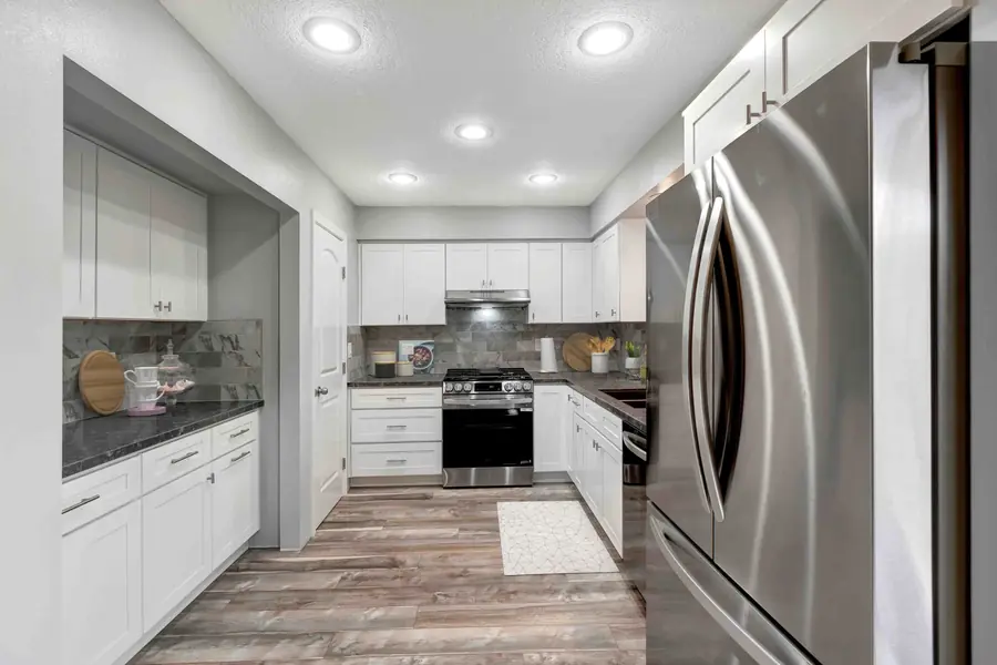 Kitchen remodel with crisp white shaker cabinets, marble-look backsplash, and LVP flooring by USA Home Remodeling