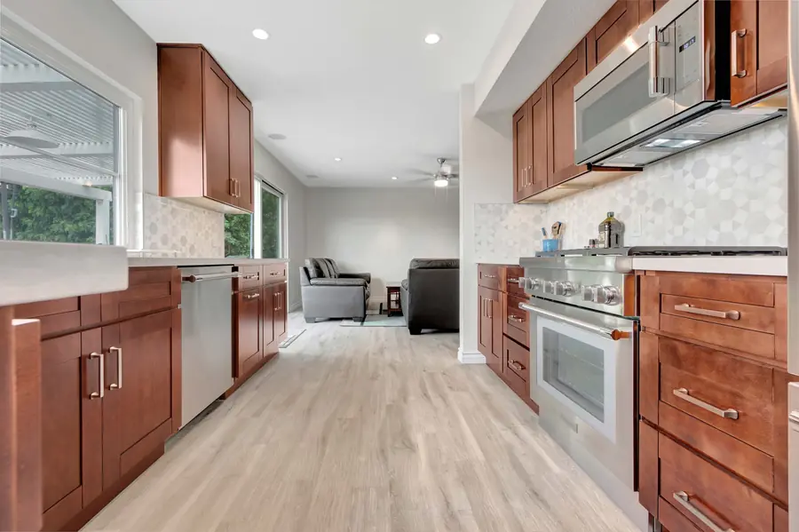Mission Viejo galley kitchen after remodel with walnut shaker cabinets, quartz countertops, geometric marble backsplash, and luxury vinyl plank flooring by USA Home Remodeling