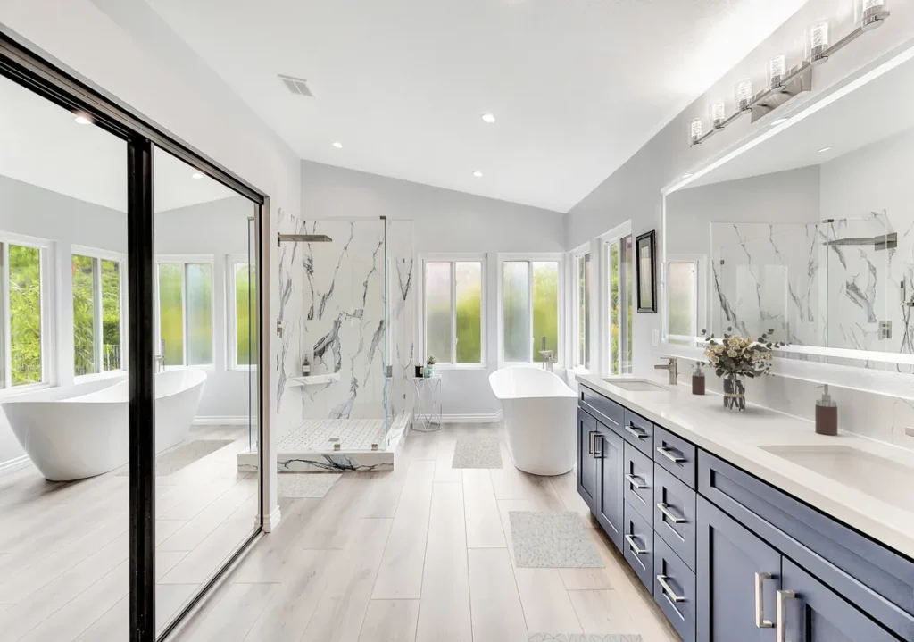 Dana Point master bathroom remodel after photo featuring a freestanding soaking tub, a navy double vanity with quartz countertops, and a Calacatta marble walk-in shower with frameless glass