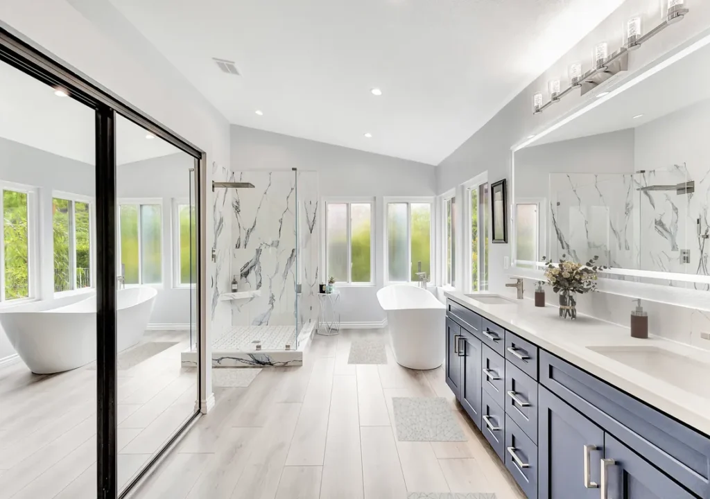 Orange master bathroom remodel after photo featuring a freestanding soaking tub, a navy double vanity with quartz countertops, and a Calacatta marble walk-in shower with frameless glass
