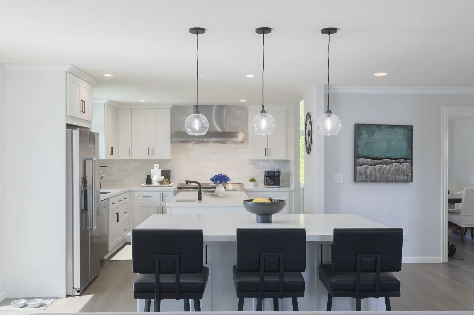 Newport Beach remodeling contractor — transitional white kitchen with quartz island, glass globe pendant lights, and stainless appliances