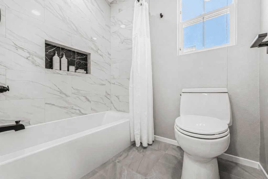 After photo of a remodeled Placentia tub-shower combo with full-height marble-look tile and matte black fixtures