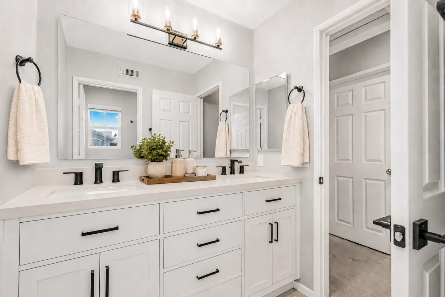 White shaker double sink vanity with matte black faucets and a brass vanity light in a Placentia bathroom remodel.