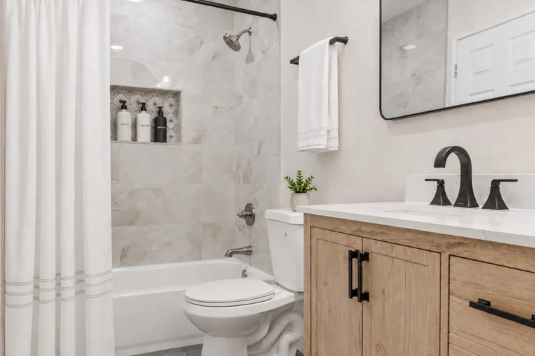 Tub shower combo, natural wood vanity, white quartz countertop, and matte black faucet in a completed Irvine bathroom remodel.