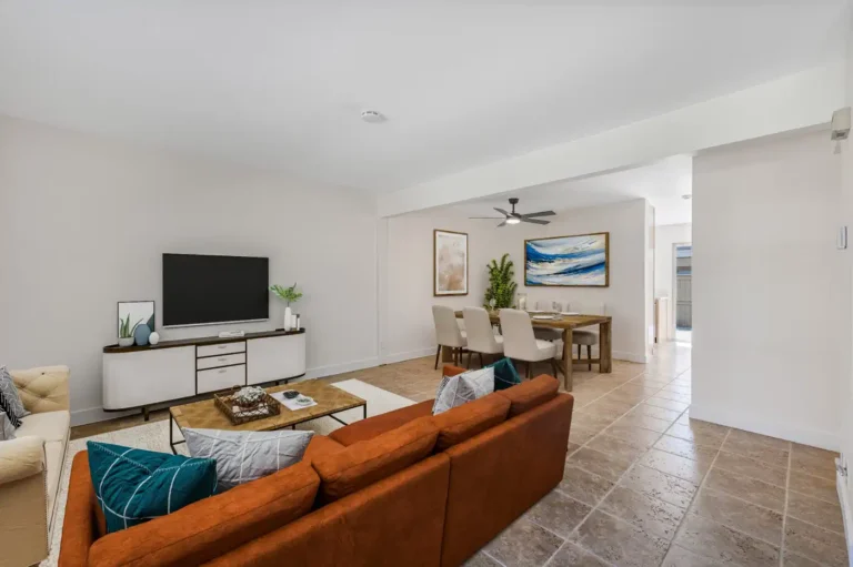 Remodeled Irvine living room with an orange sofa, neutral seating, wood coffee table, TV console, and open dining area.