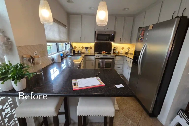 Before photo of an outdated kitchen in Carlsbad with white cabinets, dark granite countertops, stainless steel appliances, and a peninsula.