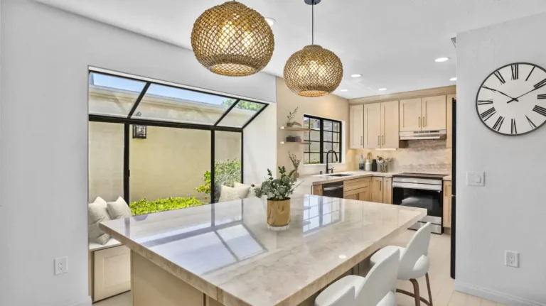 Polished stone island and black-framed window in a bright remodeled kitchen in Carlsbad.