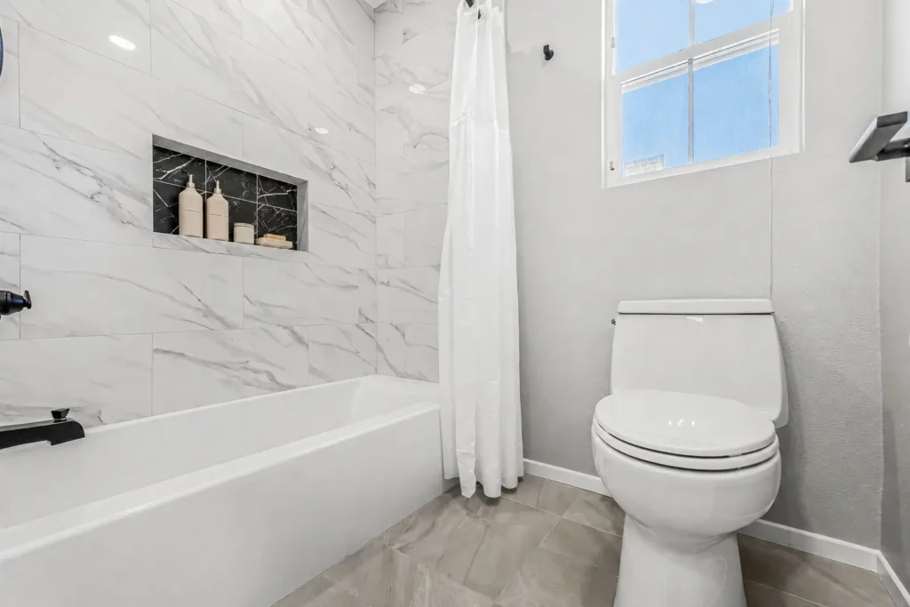 Placentia Remodeled bathroom with tub shower combo, marble-look wall tile, and modern toilet