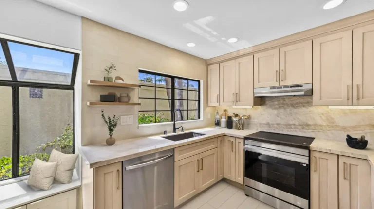 Black undermount sink and stainless steel range in a light wood kitchen remodel in Carlsbad.