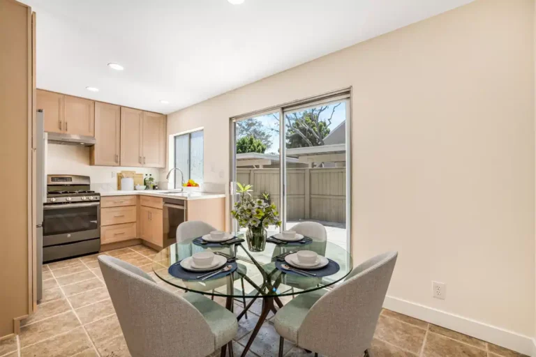 Irvine dining nook with a glass table, upholstered chairs, kitchen view, and sliding doors leading to the patio.