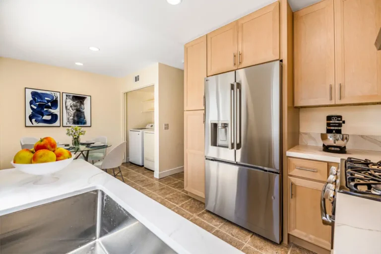 Remodeled Irvine kitchen with natural wood cabinets, stainless steel refrigerator, quartz countertops, coffee station, and adjoining dining area.