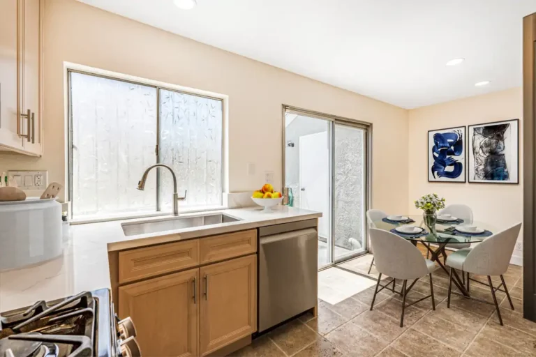 Irvine kitchen remodel with natural wood cabinets, quartz countertops, stainless steel dishwasher, dining nook, and sliding glass doors.