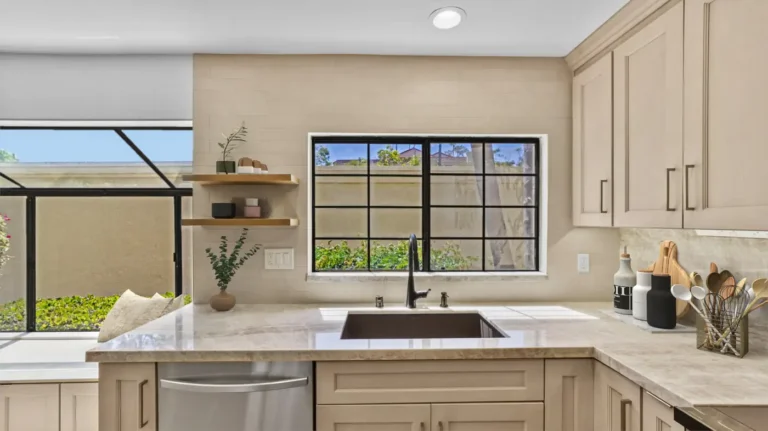 Black sink beneath a grid window with floating shelves in a remodeled kitchen in Carlsbad.