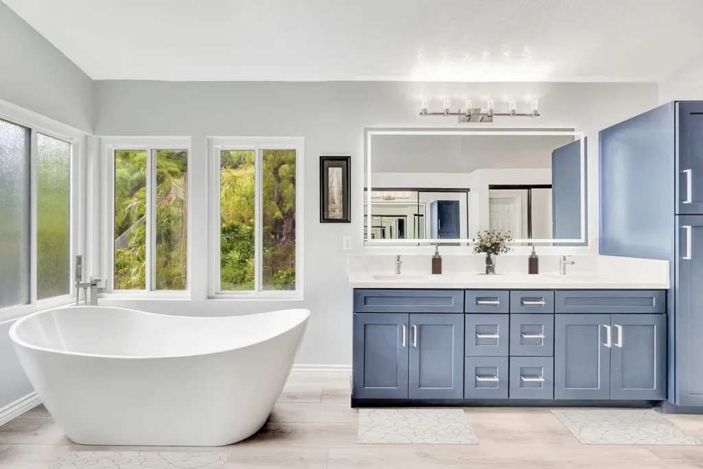 Brea master bathroom remodel after photo featuring a stunning Calacatta marble walk-in shower, a freestanding soaking tub, and a navy double vanity with quartz countertops