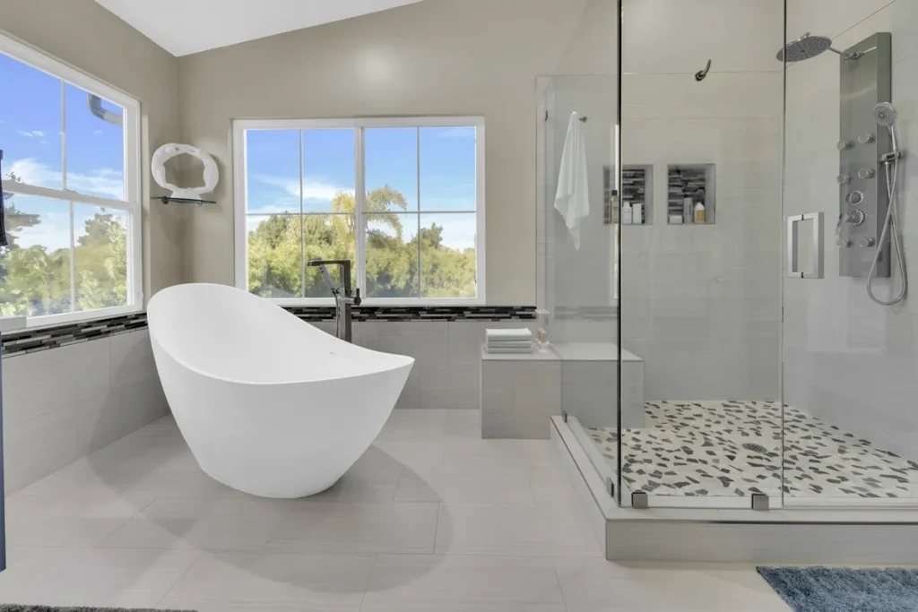 Lake Forest master bathroom remodel after photo featuring a sculptural egg-shaped soaking tub, a frameless-glass spa walk-in shower with body jets, and a pebble mosaic floor
