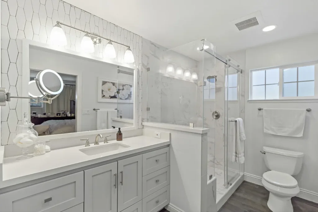 Laguna Woods guest bathroom remodel after photo featuring a bright hexagon-tile accent wall, a soft gray shaker vanity with white quartz, and a Carrara marble walk-in shower with frameless glass