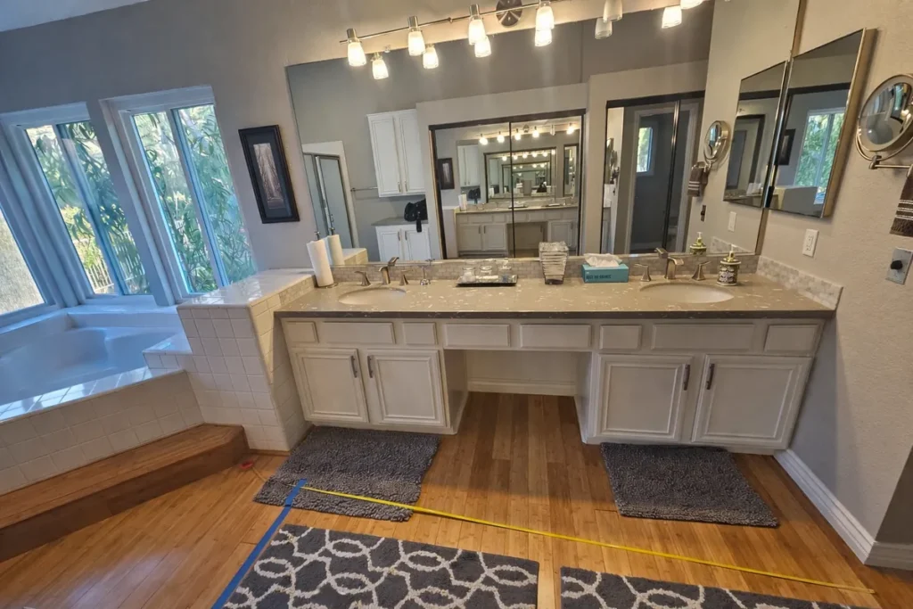Brea master bathroom before remodel with a tile-clad built-in jacuzzi, a small framed-glass shower enclosure, and mirrored closet doors