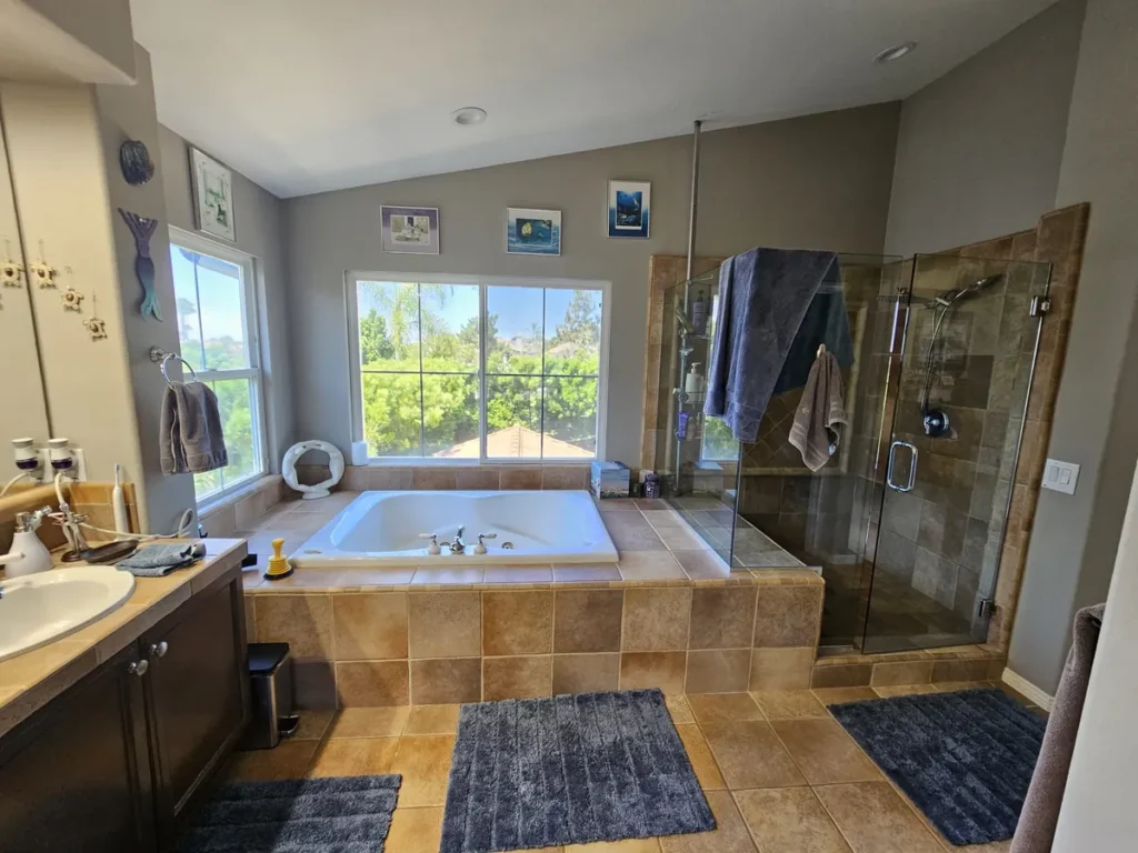 Lake Forest master bathroom before remodel with a tile-clad jetted tub and a small framed-glass shower enclosure
