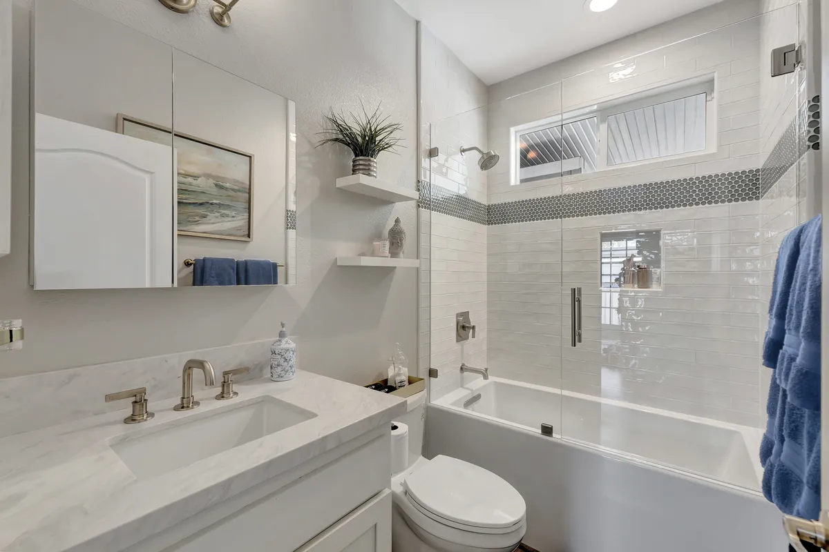Laguna Woods guest bathroom remodeling project — white marble counters, white subway tile, and penny mosaic band