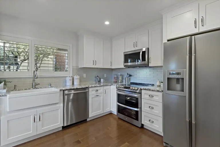 Full view of a remodeled Laguna Hills kitchen with a farmhouse sink, granite countertops, and stainless steel appliances