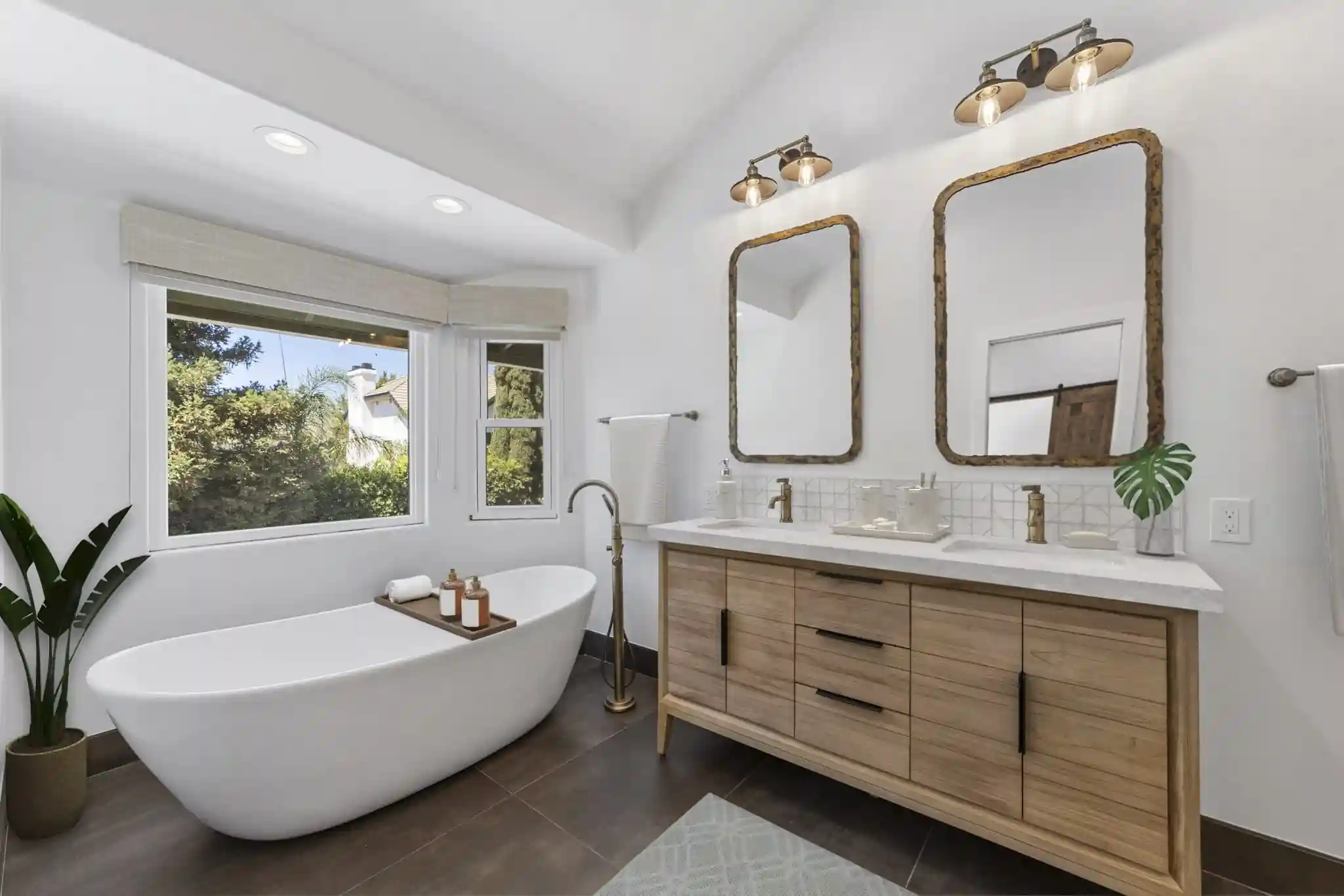 Freestanding soaking tub beside a wood double vanity in a Santa Ana master bathroom remodel