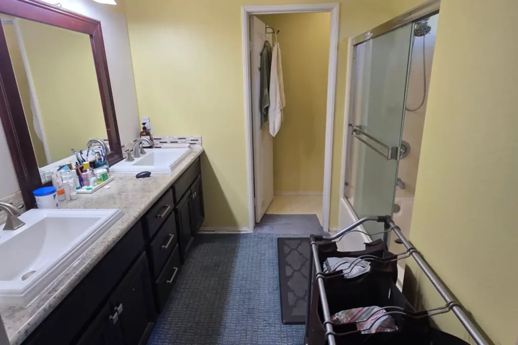Before photo of a dated Irvine, California bathroom with carpet, a dark vanity, and an enclosed tub