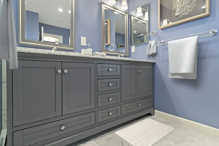 Gray double vanity with marble top, two framed mirrors and polished chrome fixtures.