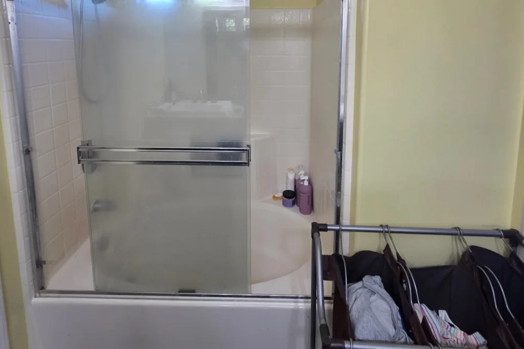 Before photo of an enclosed tub and shower combo in a dated Irvine, California bathroom