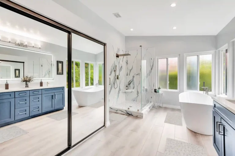 Mirrored closet doors reflecting the blue vanity and freestanding tub in a Laguna Hills primary bathroom.