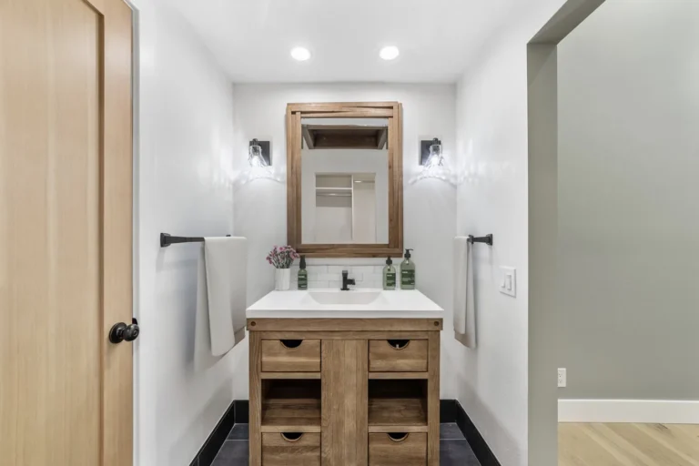 Framed wood mirror between two glass sconces above the vanity in a Santa Ana bathroom remodel