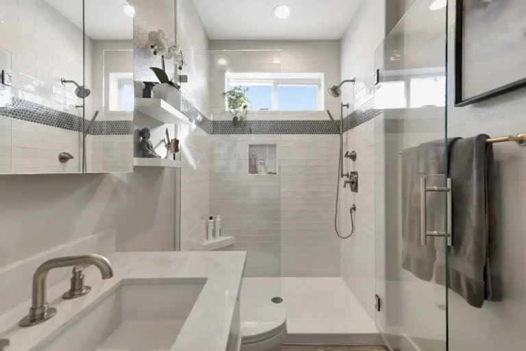 Gray penny round mosaic band running through the shower tile of a Newport Beach master bathroom