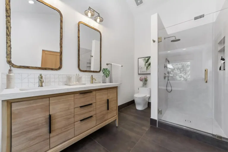 Glass walk-in shower across from a wood double vanity in a Santa Ana master bathroom remodel