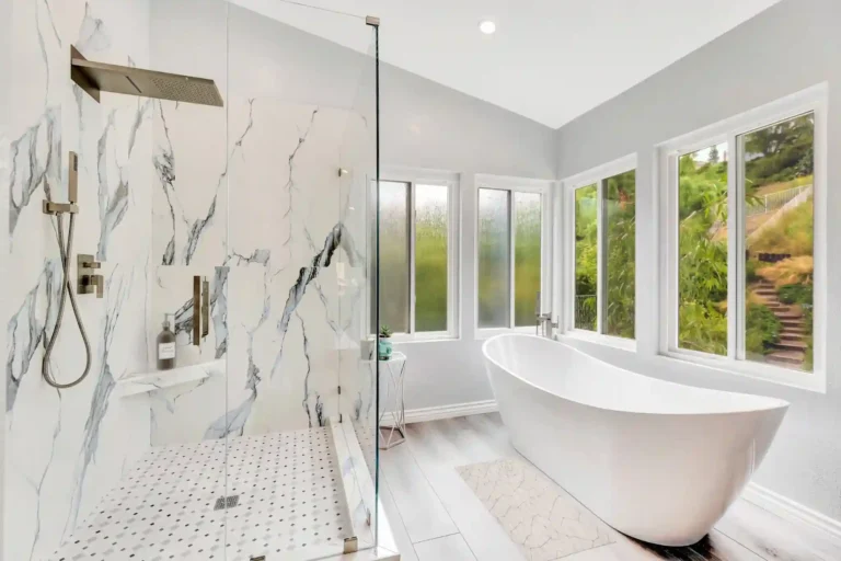 Marble-look tile shower with frameless glass beside the freestanding tub in a Laguna Hills bathroom.